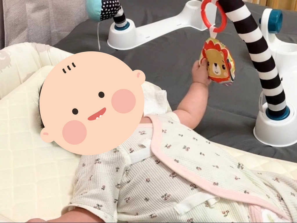 メリーの飾りを握る生後3ヶ月の赤ちゃん