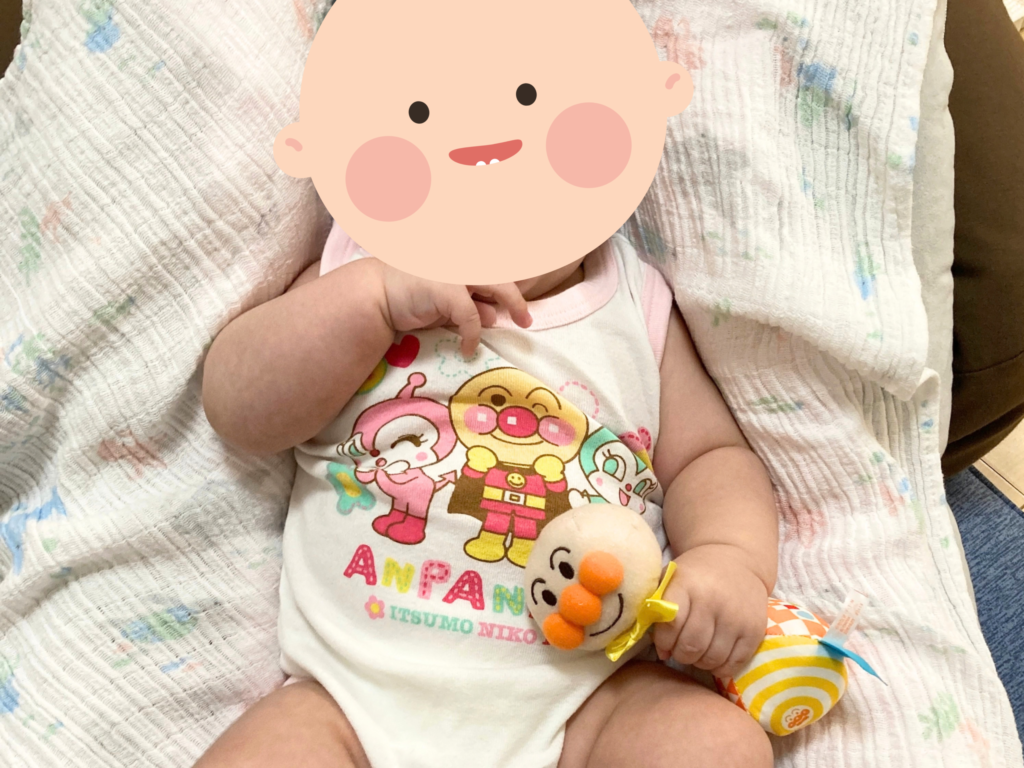 ラトルを握って遊ぶ生後3ヶ月の赤ちゃん