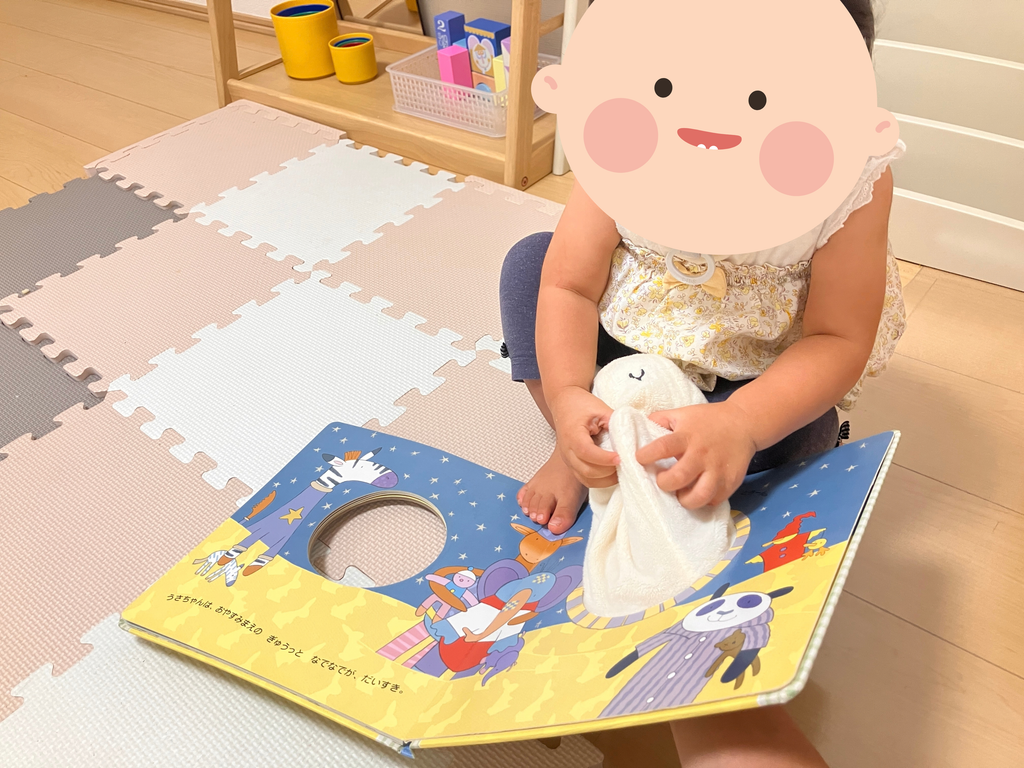 ぬいぐるみ付きの絵本で遊ぶ１歳の娘